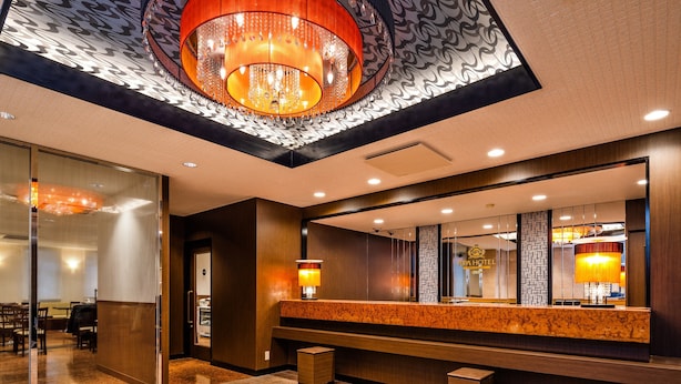 Een hotel receptie met een grote spiegel, een houten balie en een kroonluchter.