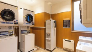 Une buanderie équipée de plusieurs machines à laver, d’un sèche-linge et d’un distributeur d’eau.