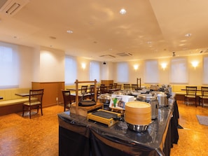Ein reichhaltiges Buffet mit mehreren Servicestationen, Stühlen und Tischen in einem großzügigen Raum mit großen Fenstern.