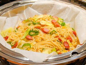 Un plat de nouilles, de légumes et de saucisses.