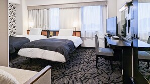 Een hotelkamer met twee bedden, een bureau met een computer, een stoel en een televisie.