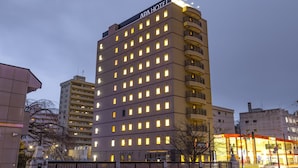 Een hotel met meerdere verdiepingen, een opvallend bord bovenaan, diverse balkons en een goed verlichte gevel.