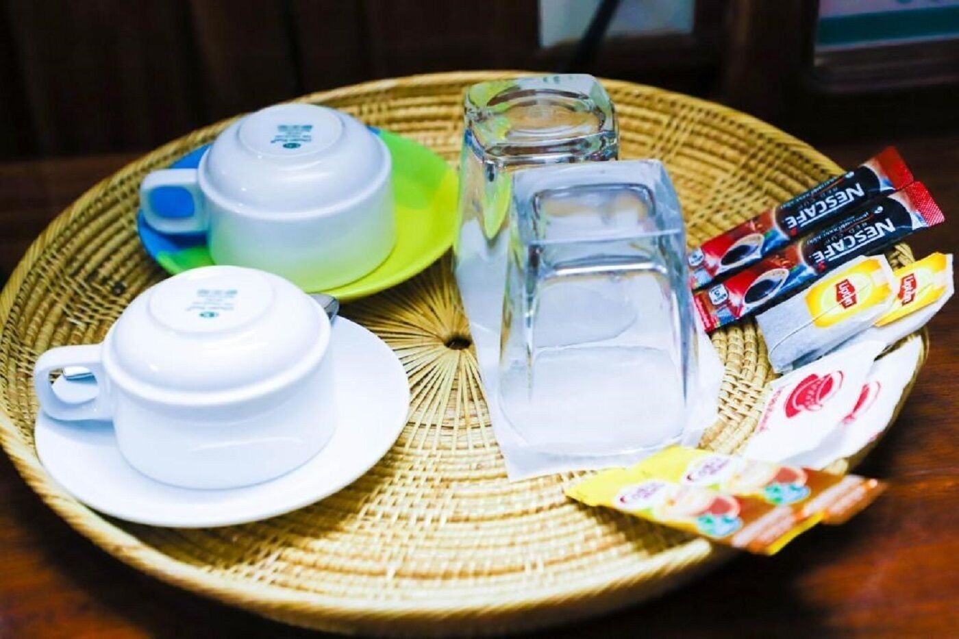 A tray with a teapot, cups, a glass, and packets of snacks.