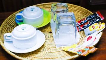A tray with a teapot, cups, a glass, and packets of snacks.