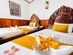 Habitación de hotel con tres camas, cabeceros de madera y un cuadro enmarcado en la pared.
