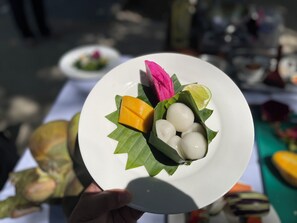 A plate with food items including a lime, a yellow fruit, and white round items, held by a person. - Okay 1 Villa (Siem Reap)