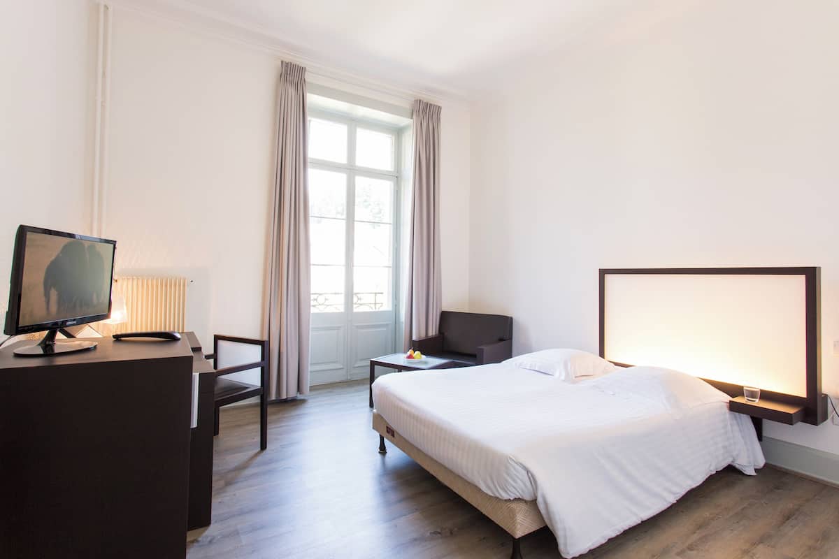 Une chambre d’hôtel comprenant un lit, un bureau avec un ordinateur, une chaise et un téléviseur.