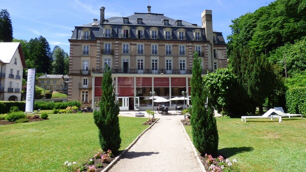 Un edificio grande e histórico con un patio central, un restaurante llamado 'Jardin des Lices' y un letrero que dice 'Restaurante'.