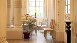 Un pasillo con columnas blancas, una planta en maceta y una mesa con sillas.