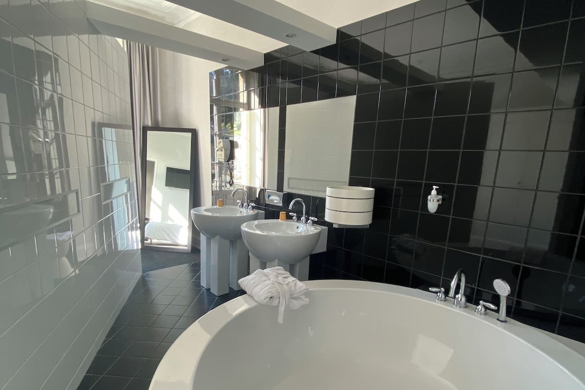 Une salle de bain moderne avec une grande baignoire, deux lavabos et un miroir.