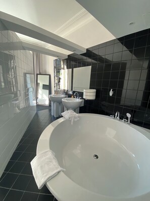Une salle de bain moderne avec une grande baignoire, deux lavabos et un miroir.