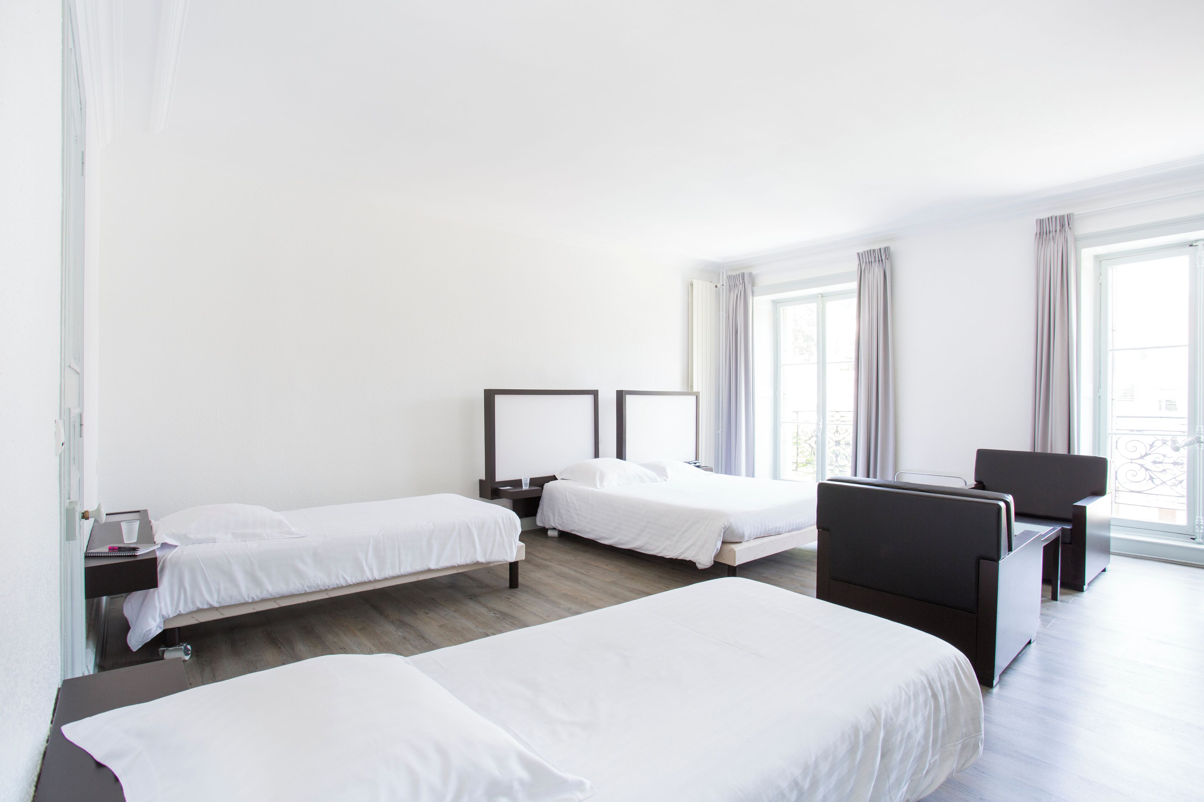 A hotel room with two single beds, a desk, and a chair.
