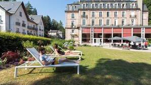 Un hotel con un edificio grande, un área de estar al aire libre y un jardín bien cuidado.
