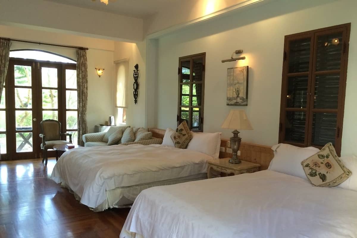 A bedroom with two beds, a chair, and a table.