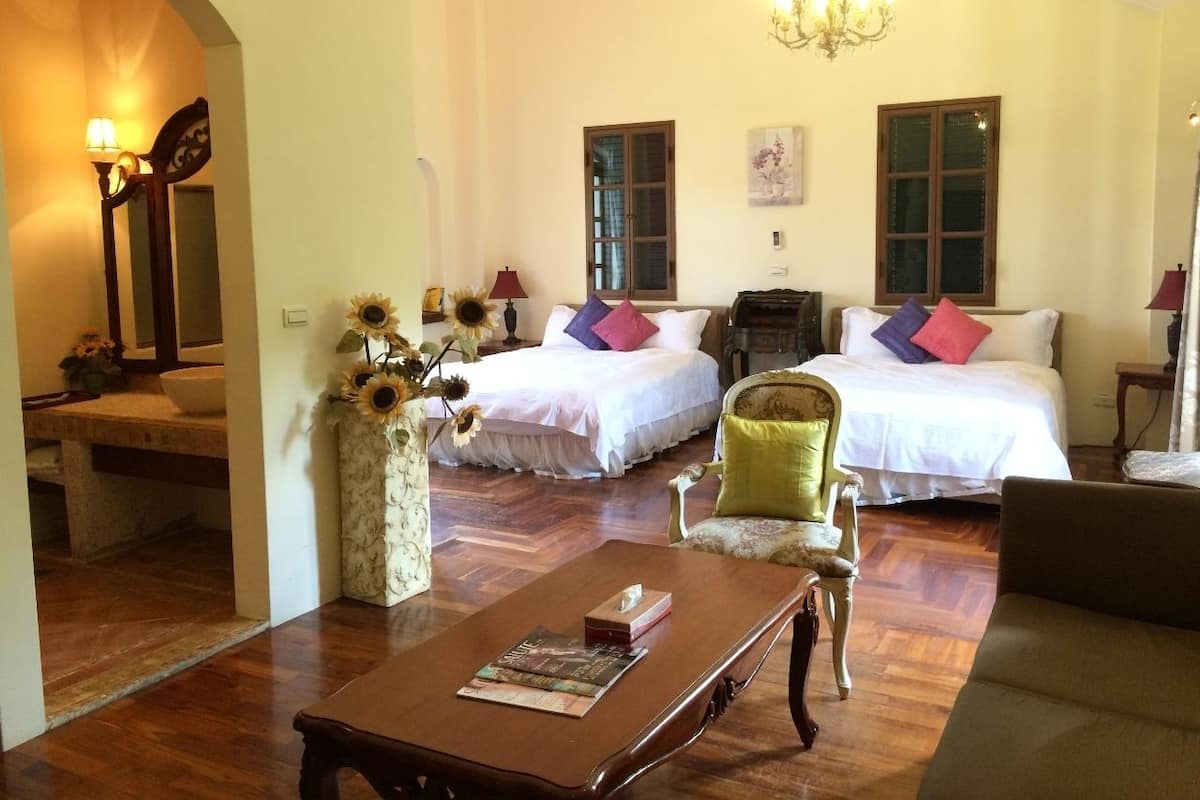 A hotel room with two beds, a sitting area with a table, and a large window.