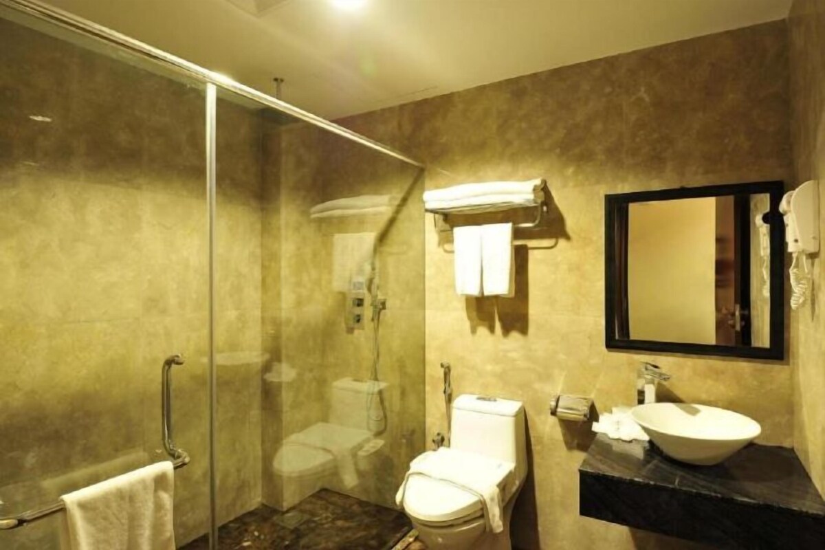 A bathroom with a glass-enclosed shower, a toilet, a sink with a mirror, and a towel rack.