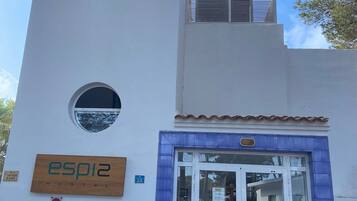 Un bâtiment sur lequel on peut lire l’inscription « esp12 HOSTAL » et où le chiffre « 28 » est peint sur le mur. La façade comporte deux fenêtres de forme circulaire.