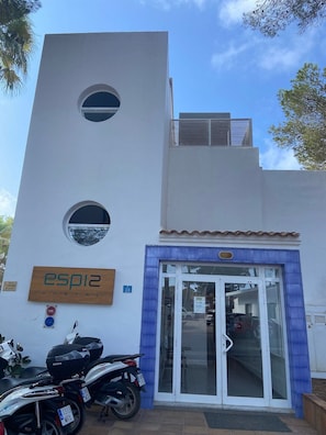 A building with a sign reading 'esp12 HOSTAL' and a number '28' on the wall. There are two circular windows on the facade.