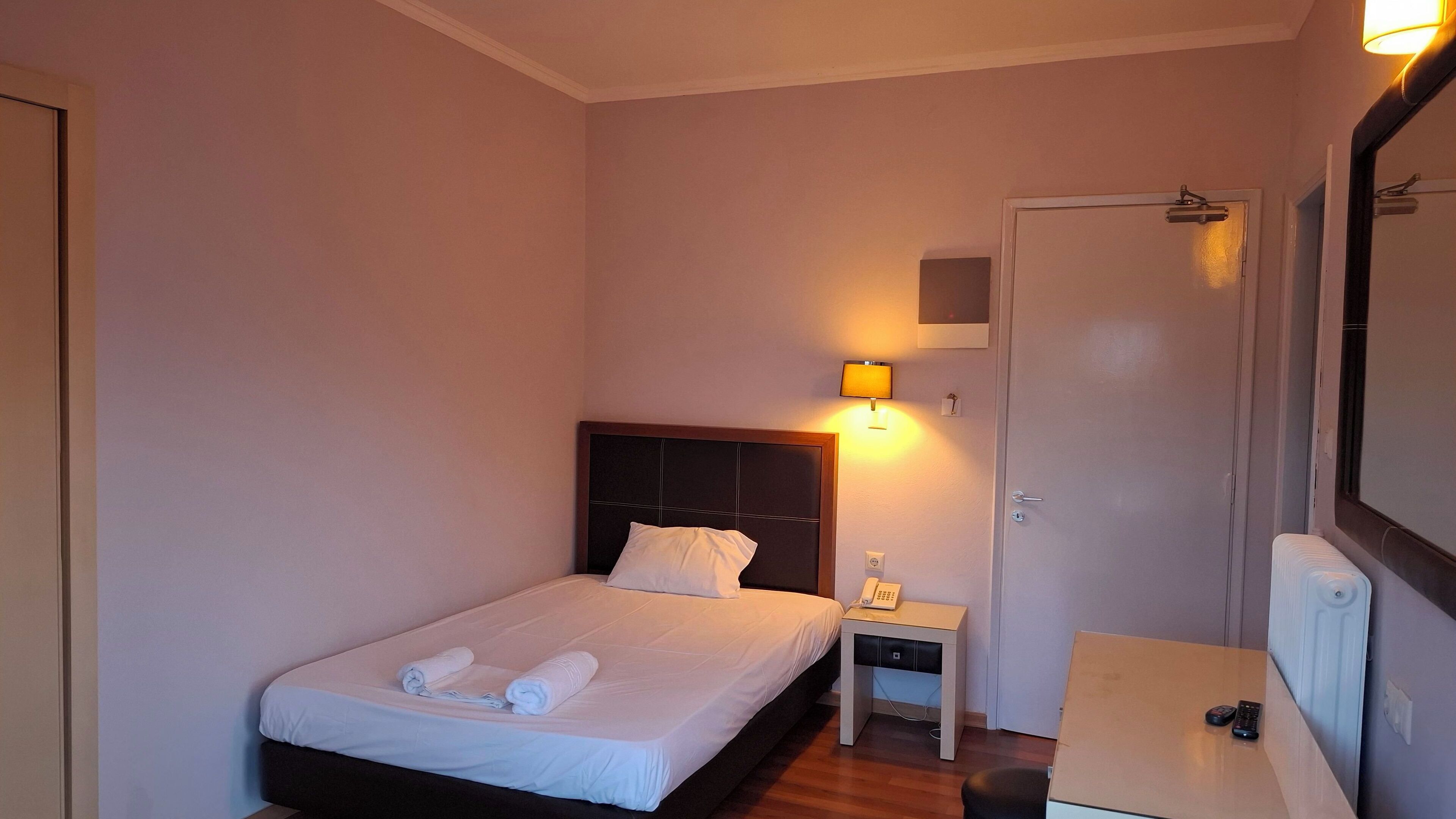 Une chambre d’hôtel avec un lit, une table de chevet, une lampe et un miroir.