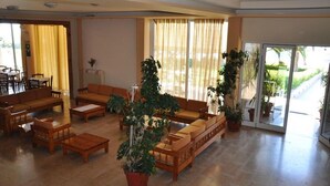 A spacious living area with a sofa set, wooden coffee table, and potted plants. - Elena Hotel (Lokroi)