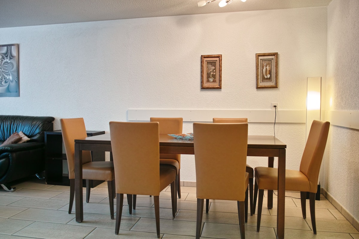 Un comedor con mesa y sillas, un sofá y dos cuadros en la pared.