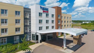 A multi-story Fairfield Inn & Suites hotel with a modern design, featuring a covered entrance and a parking lot.