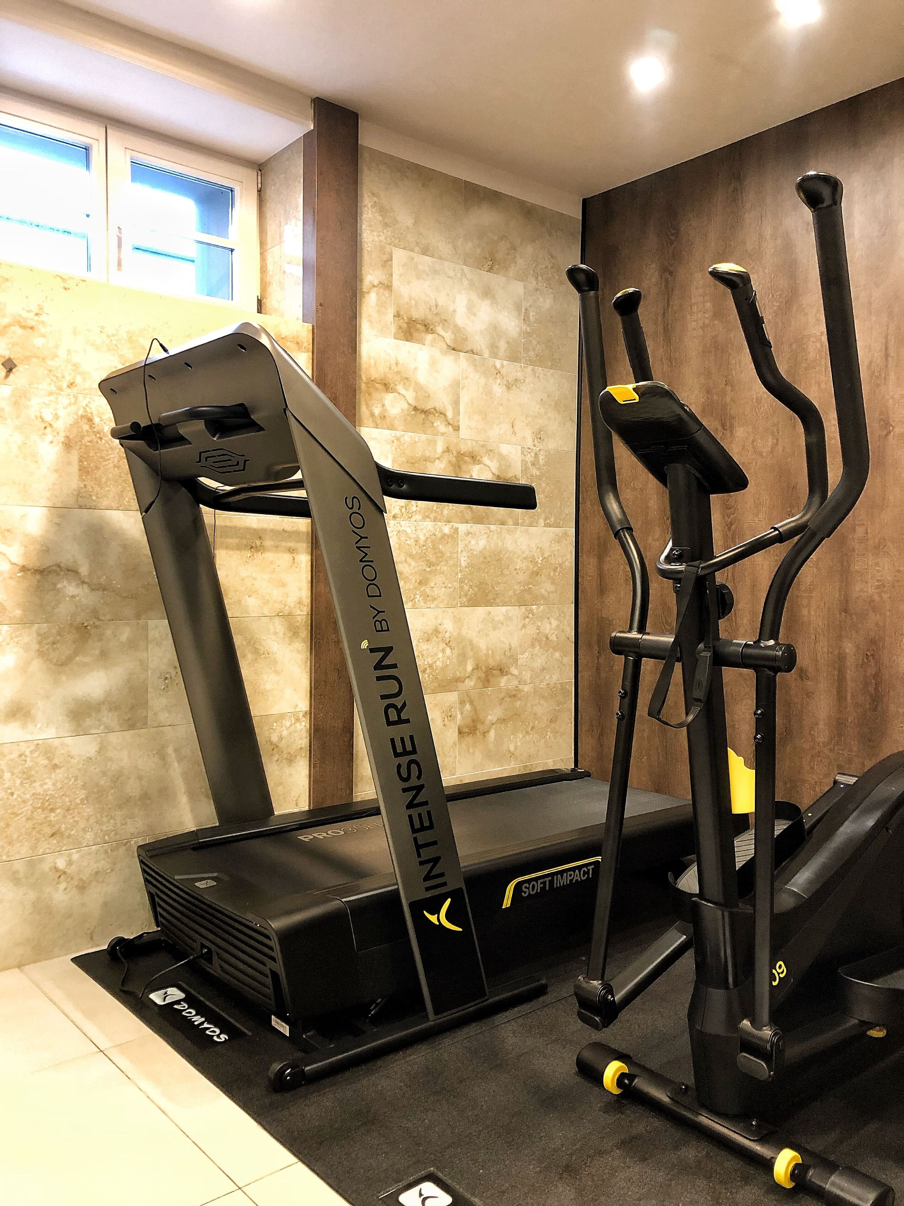 Un gimnasio con cinta de correr, elíptica y bicicleta estática.