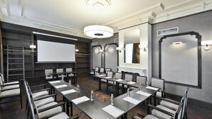 A conference room with a long table, chairs, a projector screen, and a whiteboard. - Hotel Red Baron (Swidnica)