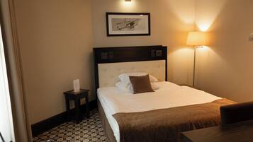 Habitación de hotel con cama, mesita de noche, lámpara y un cuadro en la pared.