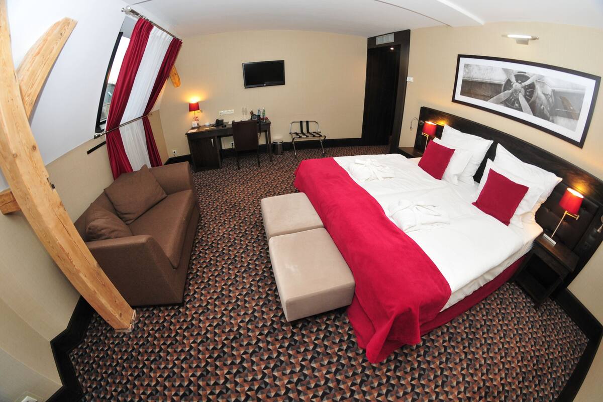 A hotel room with a bed, a desk, a chair, and a television.