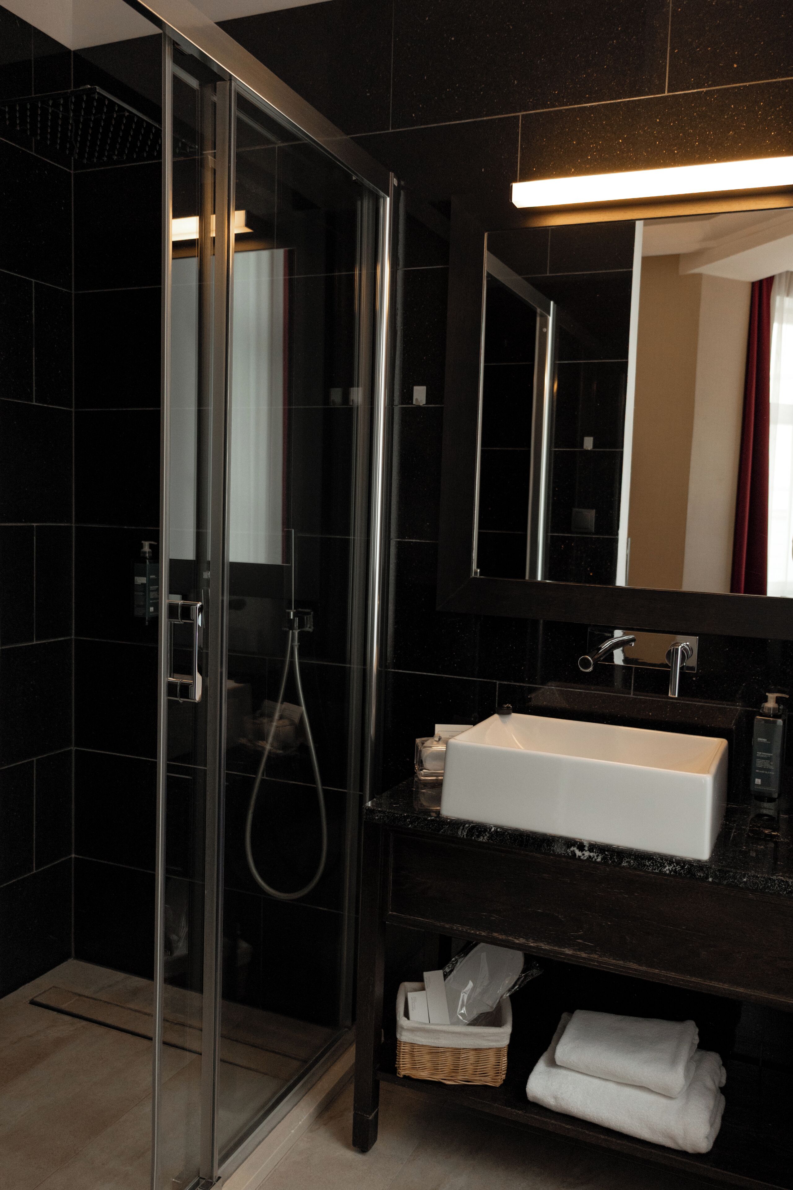 A modern bathroom with a glass-enclosed shower, a white sink, and a large mirror.