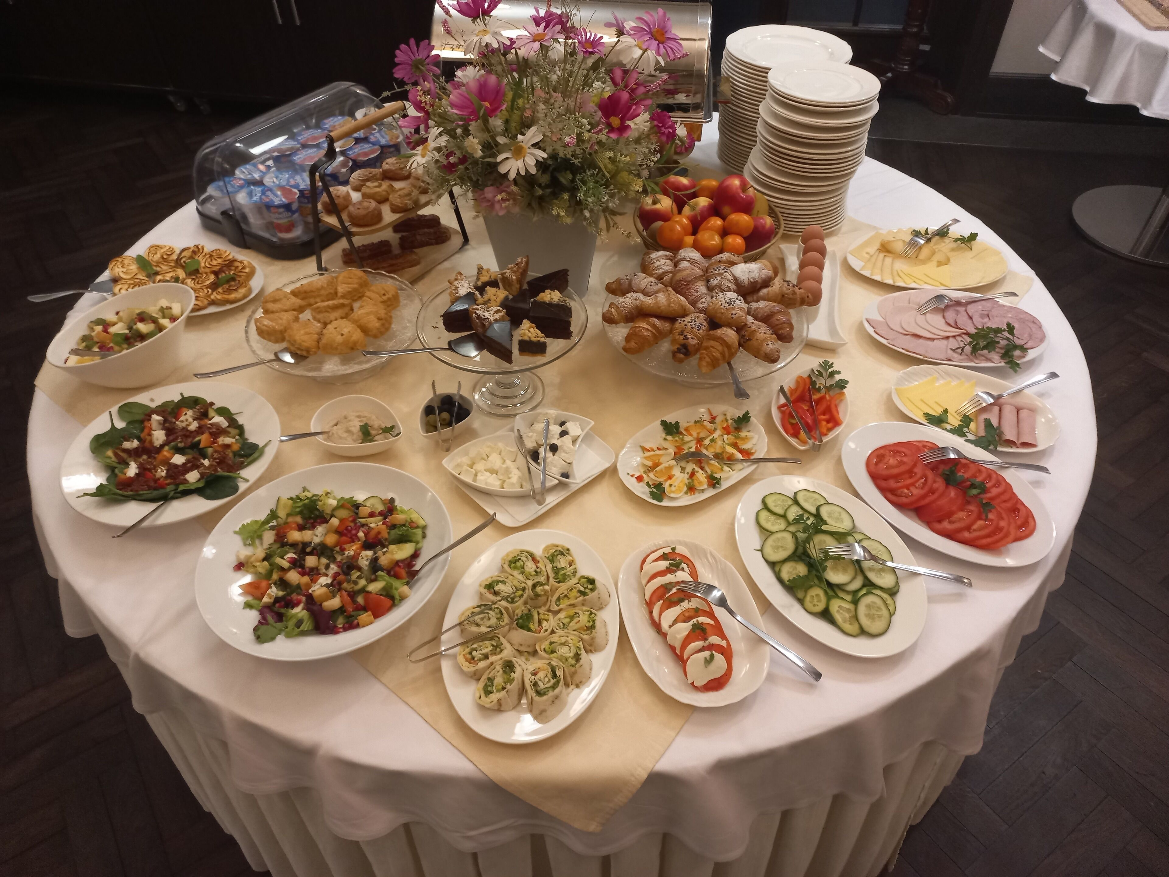 A buffet table with various food items, including salads, pastries, and fruits.