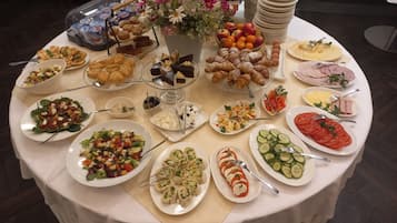 A buffet table with various food items, including salads, pastries, and fruits.