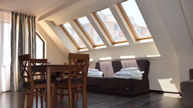 A modern loft bedroom with skylights, a dining area, and a sofa. - City Hotel Blagoevgrad (Blagoevgrad)