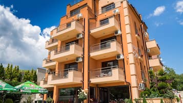 A multi-story building with balconies, air conditioning units, and a storefront with outdoor seating.