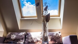 A room with a skylight, a sofa with floral cushions, and a vase with dried plants. - City Hotel Blagoevgrad (Blagoevgrad)