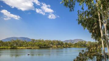 A calm lake with a boat, surrounded by trees and mountains under a clear sky.