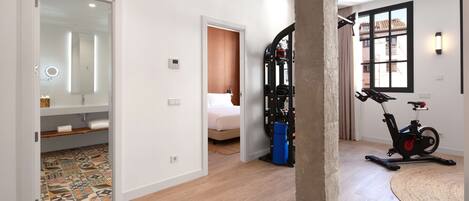 Une chambre d’hôtel avec un lit, une salle de bain avec un miroir, un tapis de course et une grande fenêtre.