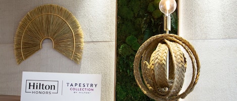 A display of two wall-mounted tapestry pieces, one with a fan-like design and the other spherical, with a sign indicating they are part of the Hilton Tapestry Collection.