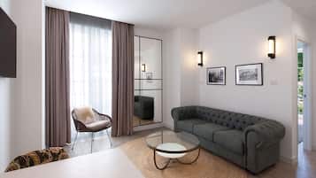 A modern living room with a sectional sofa, a glass coffee table, a wicker chair, and a large window with curtains.