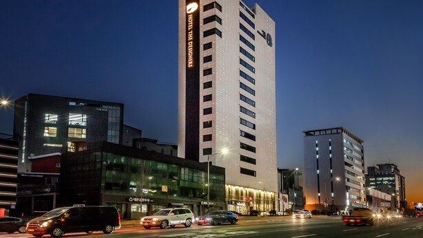 A modern hotel with a prominent sign, multiple floors, and a well-lit facade. - Hotel The Designers Hongdae (Seoul)