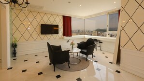 A modern hotel room with a large window offering a city view, a flat-screen TV mounted on the wall, and a seating area with two chairs and a small table. - Hotel The Designers Hongdae (Seoul)