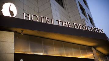 Hotel The Designers features a prominent entrance sign above its stone facade.