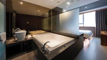 A modern bathroom with a large bathtub, a separate sink, and a mirror.