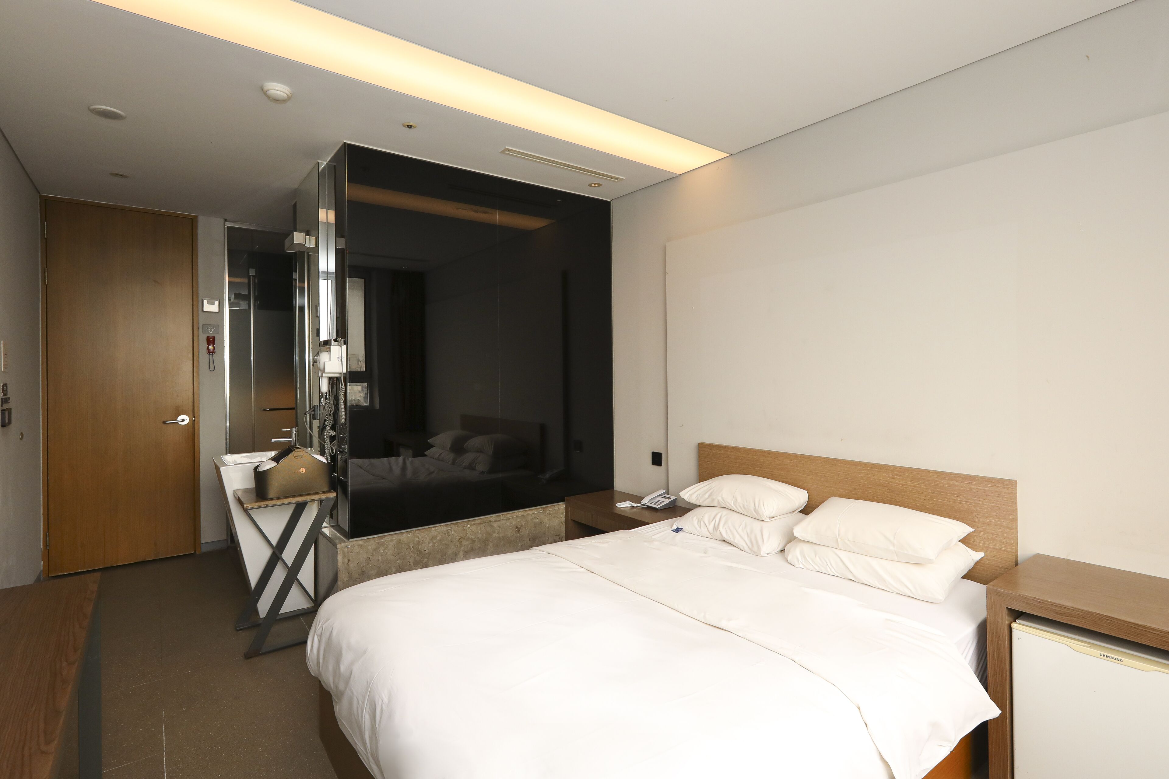 Una habitación de hotel con cama, mesita de noche y espejo.