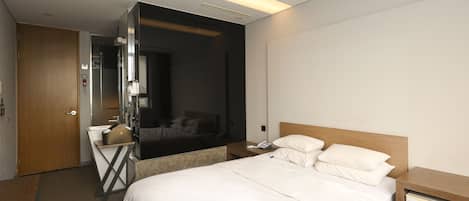 Una habitación de hotel con cama, mesita de noche y espejo.