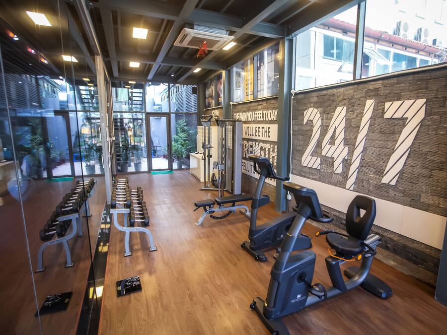Un gimnasio con equipo de ejercicio, una frase motivacional en la pared y grandes ventanales.