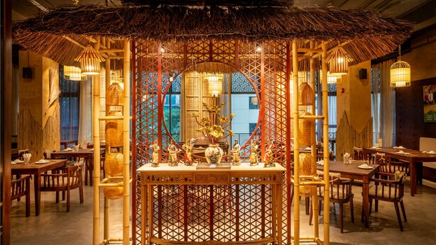 Un restaurante con estructura central de bambú, mesas y sillas de madera.