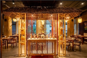 A restaurant with a central bamboo structure, wooden tables, and chairs. - My Way Hotel & Residence (Hanoi)