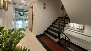 Un intérieur moderne comprenant un escalier, un couloir et une porte vitrée donnant sur un espace extérieur.